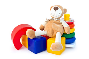 Image of a teddy bear sitting on top of some toy blocks